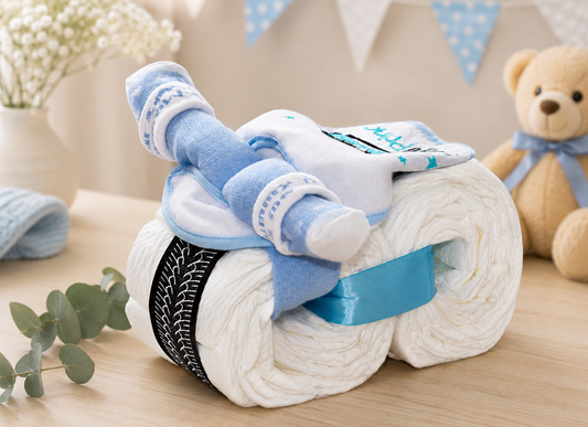 Blue mini diaper motorcycle on a wooden table with bunting, flowers, eucalyptus and a teddy bear.