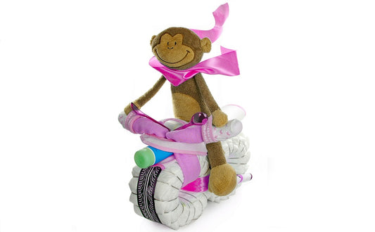 Pink diaper motorcycle with brown floppy monkey, sock handlebars and baby-care product on a white background