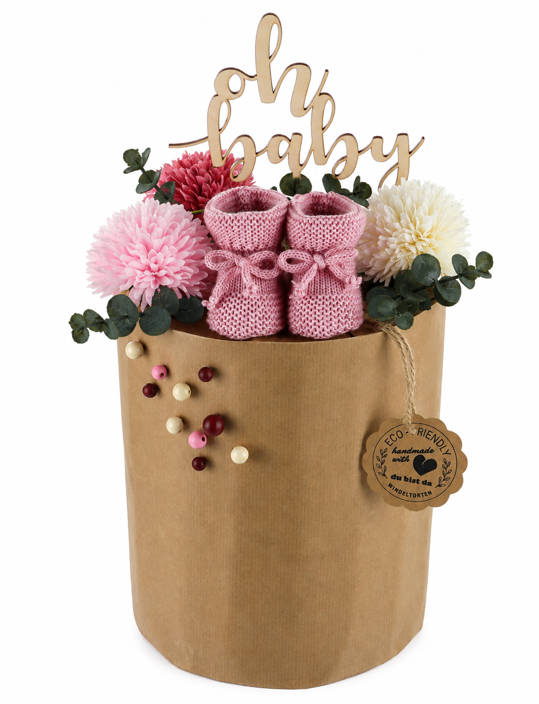 Medium kraft-paper diaper cake with pink knitted booties, flowers, eucalyptus and “Oh Baby” topper