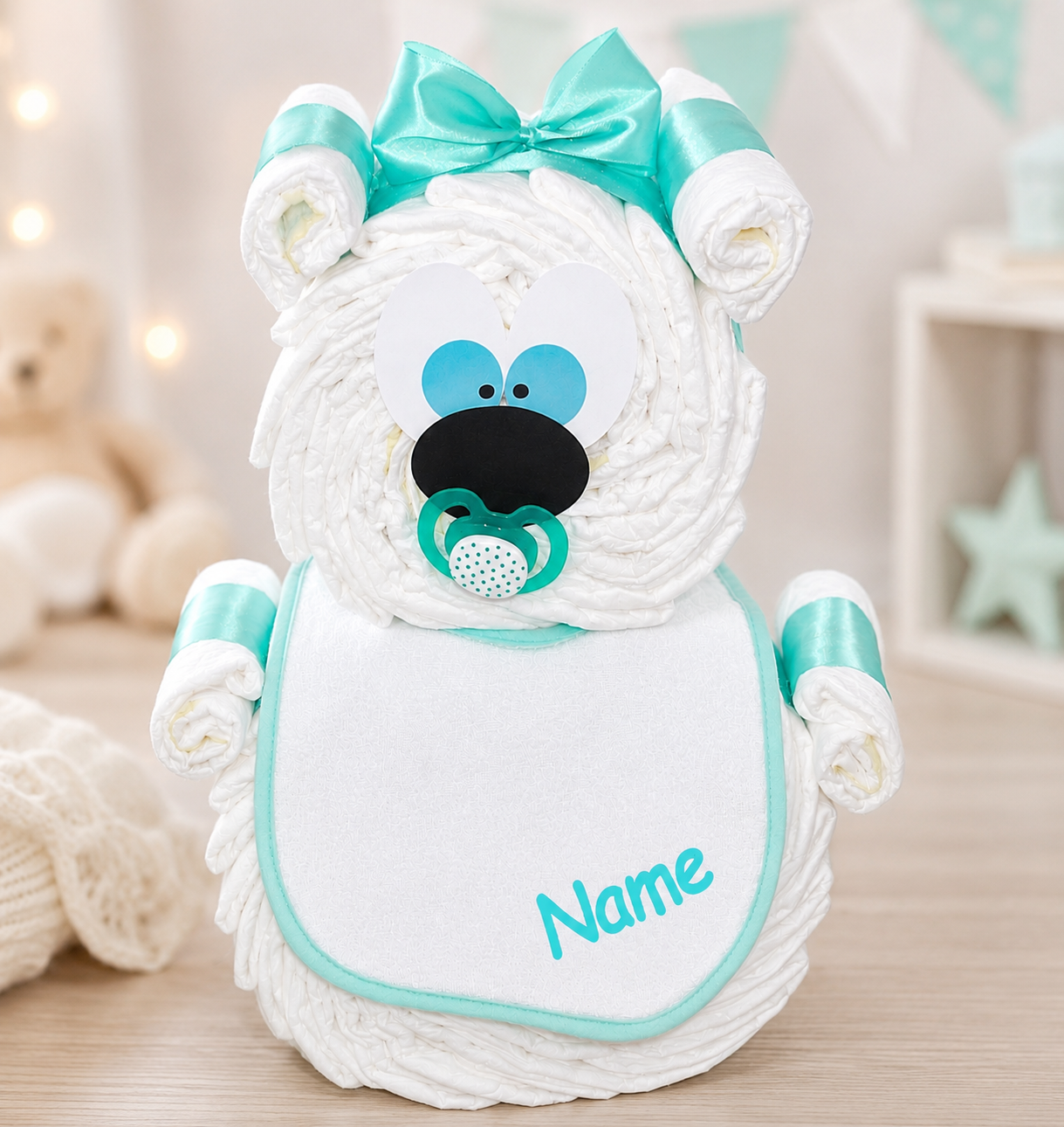Turquoise diaper bear with bow, pacifier and personalised bib in a softly styled nursery