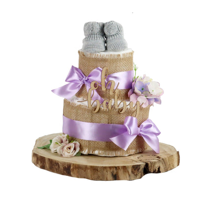 Alles Jute lilac diaper cake with grey baby booties, wooden lettering and flowers on a wood slice